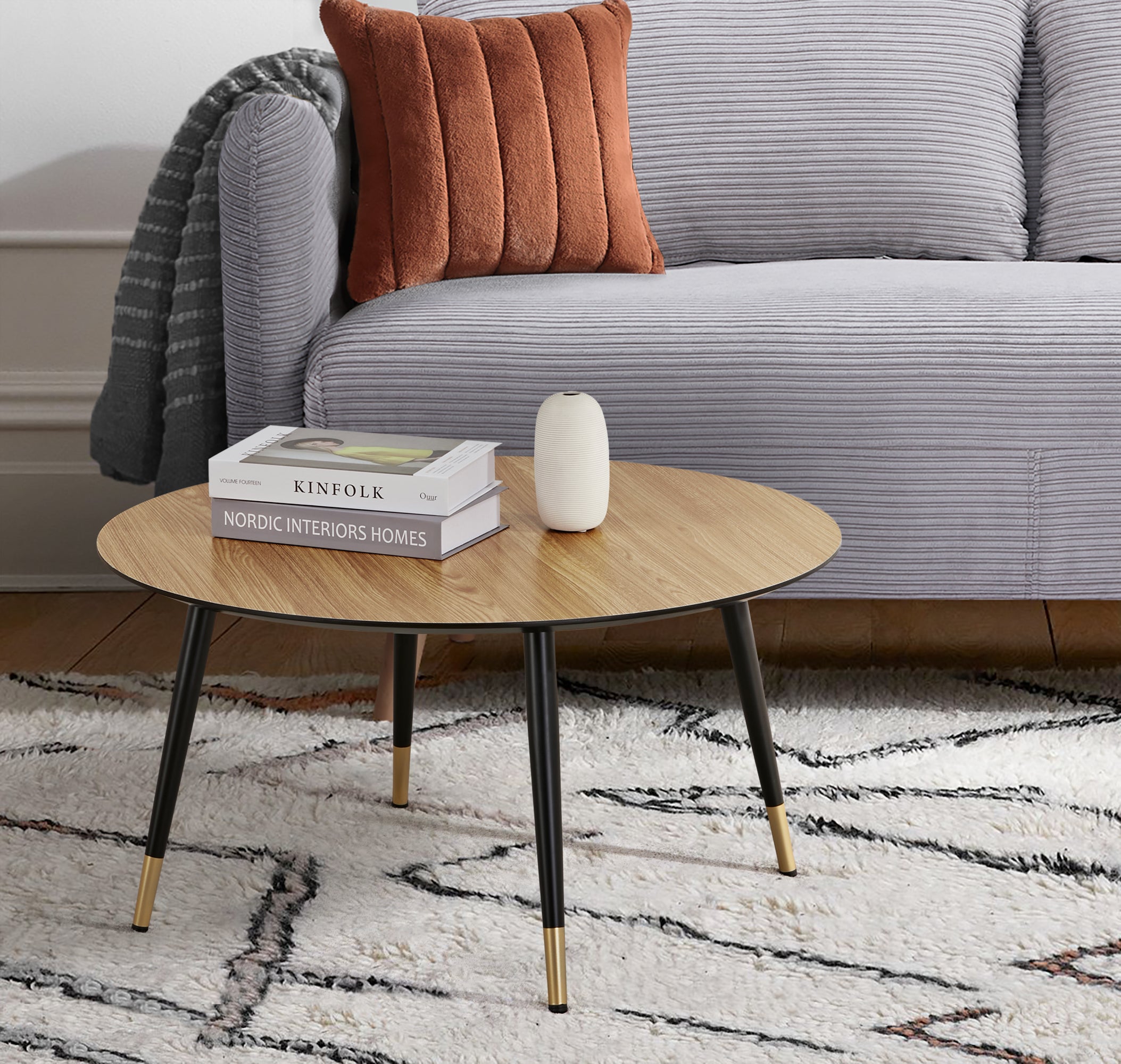 Vue d’ambiance de la table basse ronde MATIS diamètre 80 cm en finition mélaminé imitation chêne avec le canapé-lit BZ ARI en finition tissu velours côtelé